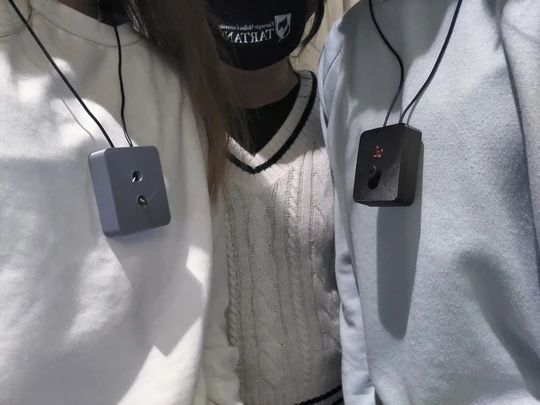 Two team members wearing the finished SafeT necklace pendants, showing the 3D-printed housings with integrated LED indicators